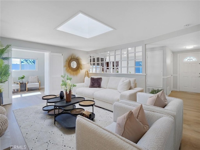 living room with light wood-type flooring and a skylight