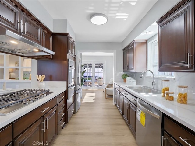 kitchen featuring appliances with stainless steel finishes, light wood-type flooring, tasteful backsplash, french doors, and sink