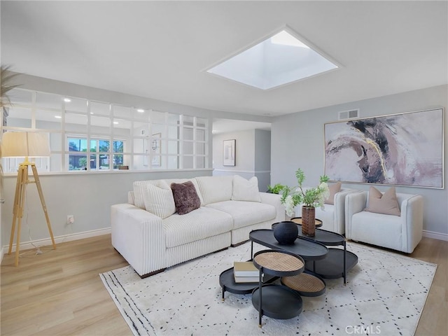 living room with light hardwood / wood-style flooring and a skylight