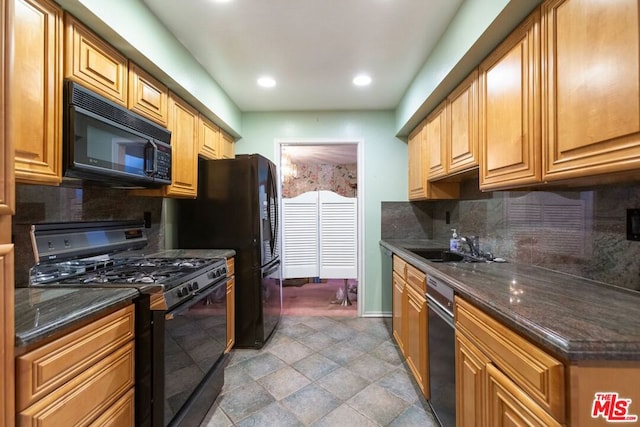 kitchen with backsplash, sink, dark stone counters, and black appliances