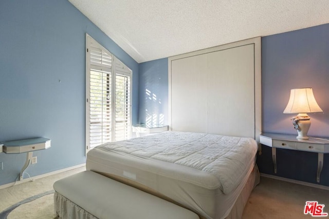 carpeted bedroom with a textured ceiling and lofted ceiling