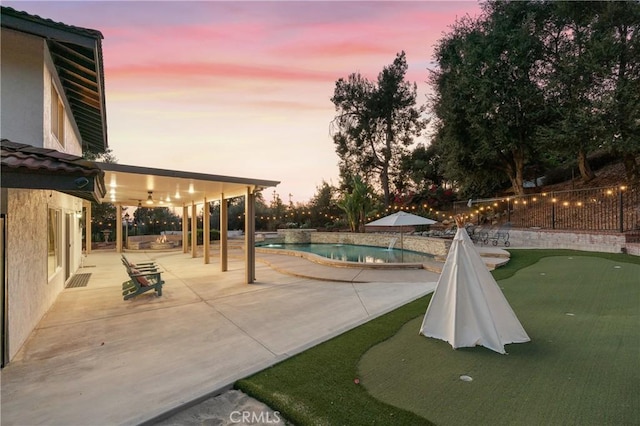 pool at dusk with a patio area