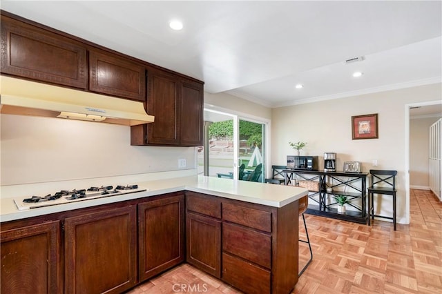 kitchen with white gas cooktop, light parquet floors, crown molding, a kitchen bar, and kitchen peninsula