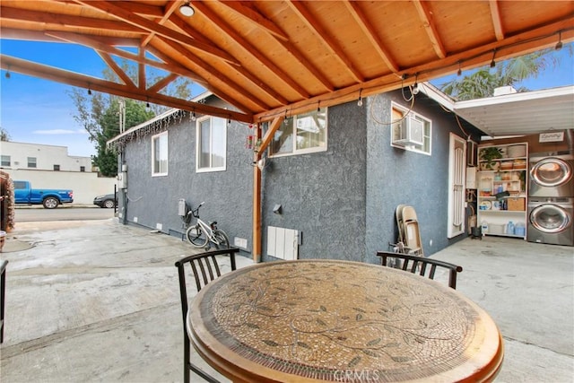 view of patio / terrace with stacked washer / dryer and a wall mounted air conditioner