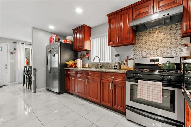 kitchen with light stone counters, sink, backsplash, and stainless steel appliances