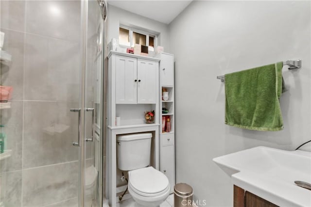 bathroom with toilet, vanity, and a shower with door