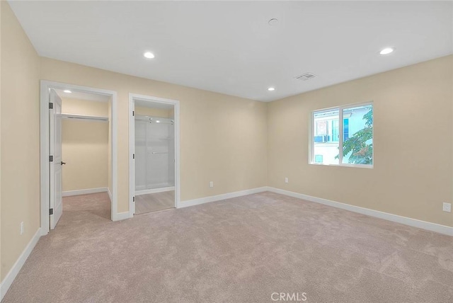 unfurnished bedroom with light carpet, a spacious closet, and a closet