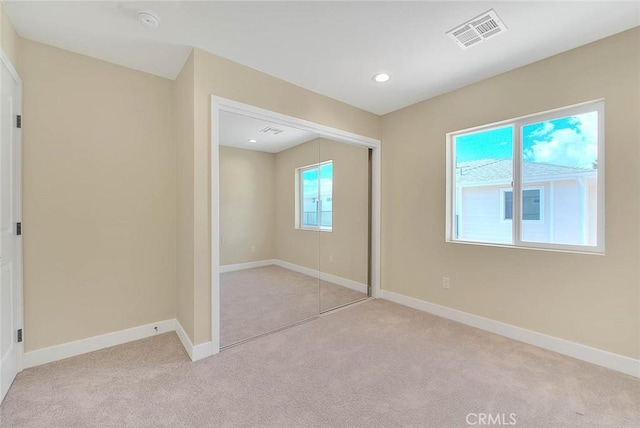 unfurnished bedroom featuring light carpet and a closet