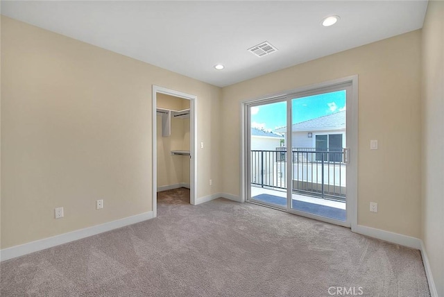 unfurnished bedroom featuring access to exterior, a spacious closet, a closet, and light carpet