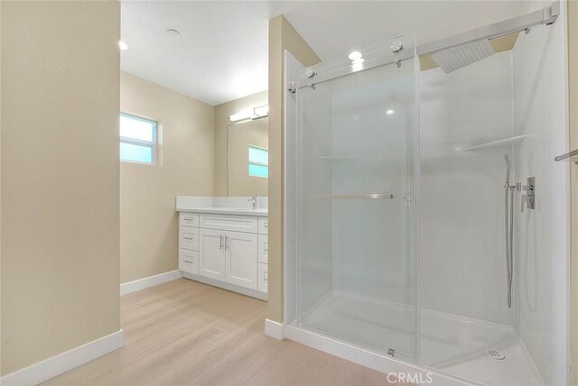 bathroom with wood-type flooring, vanity, and walk in shower