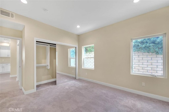 unfurnished bedroom featuring light carpet and a closet