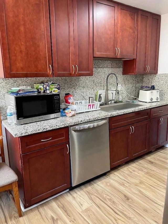 kitchen featuring light stone counters, sink, light wood-type flooring, and appliances with stainless steel finishes