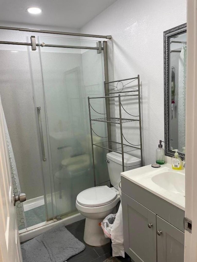 bathroom with vanity, toilet, and a shower with shower door