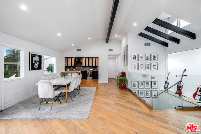 dining room featuring vaulted ceiling with beams and light hardwood / wood-style flooring