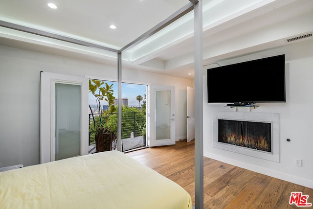 bedroom featuring hardwood / wood-style floors, access to exterior, and beamed ceiling