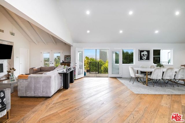 living room featuring beam ceiling, high vaulted ceiling, light hardwood / wood-style flooring, and french doors