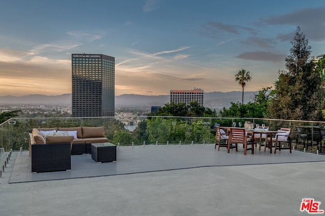 patio terrace at dusk featuring a mountain view and an outdoor living space