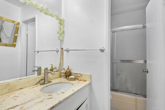 bathroom with vanity and bath / shower combo with glass door