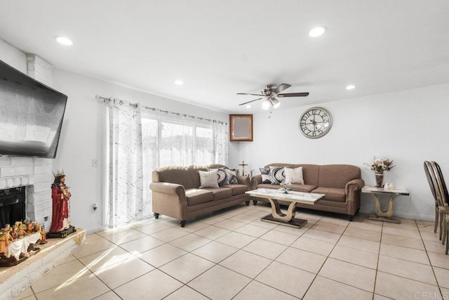 living area with light tile patterned floors, recessed lighting, a ceiling fan, baseboards, and a brick fireplace