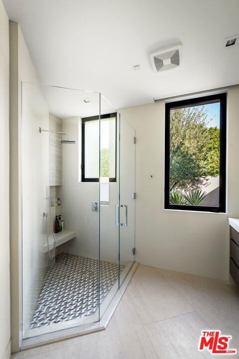 bathroom featuring a shower with door and vanity