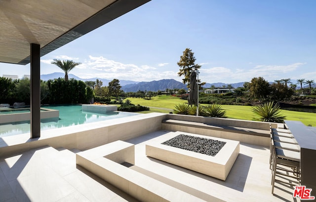 view of swimming pool with a mountain view, a patio, and an outdoor fire pit