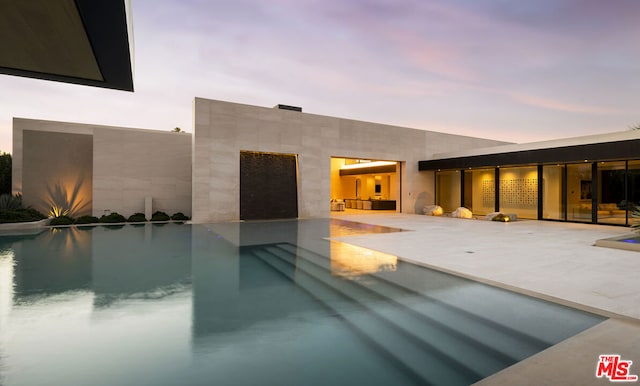 pool at dusk with a patio