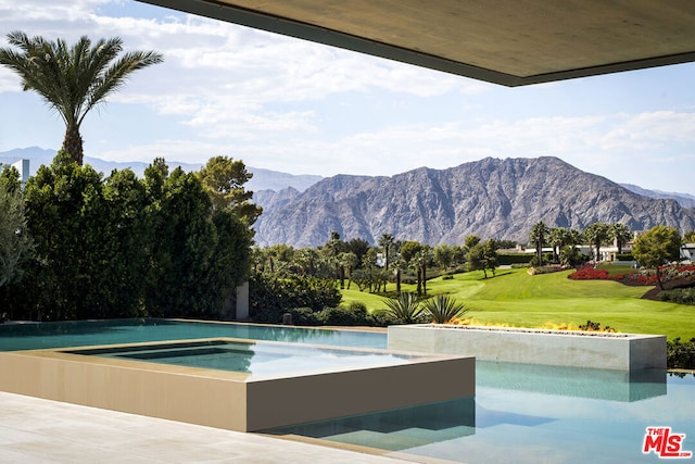 view of swimming pool with a lawn and a mountain view