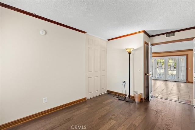 empty room featuring french doors, dark hardwood / wood-style floors, and a textured ceiling