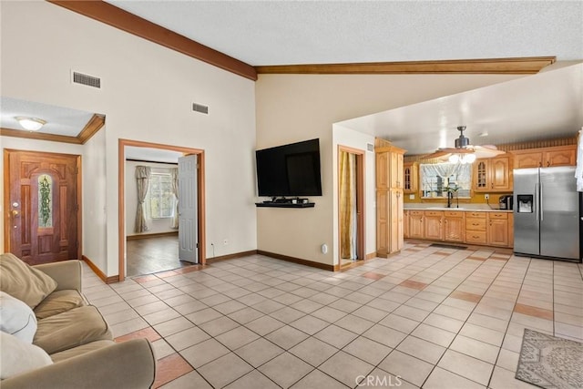 unfurnished living room featuring crown molding, light tile patterned floors, sink, high vaulted ceiling, and ceiling fan