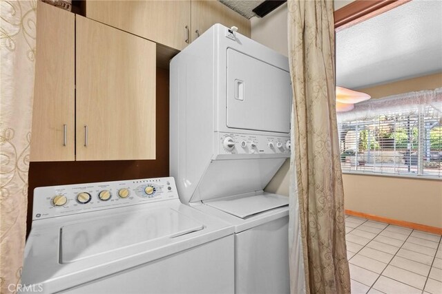 laundry area with light tile patterned floors and stacked washer and clothes dryer