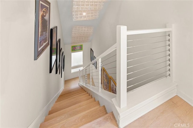 staircase with an inviting chandelier and hardwood / wood-style flooring