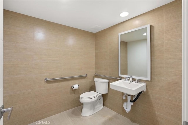 bathroom featuring tile patterned floors, toilet, and tile walls