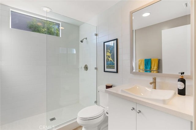 bathroom featuring a tile shower, vanity, and toilet