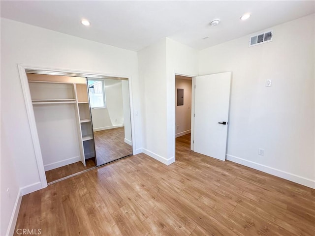 unfurnished bedroom featuring electric panel, a closet, and light wood-type flooring