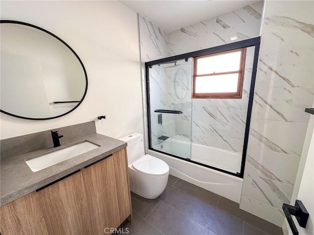 full bathroom with tile patterned flooring, vanity, bath / shower combo with glass door, and toilet