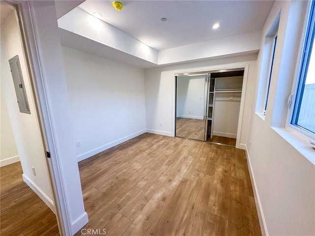 unfurnished bedroom featuring light wood-type flooring, electric panel, and a closet