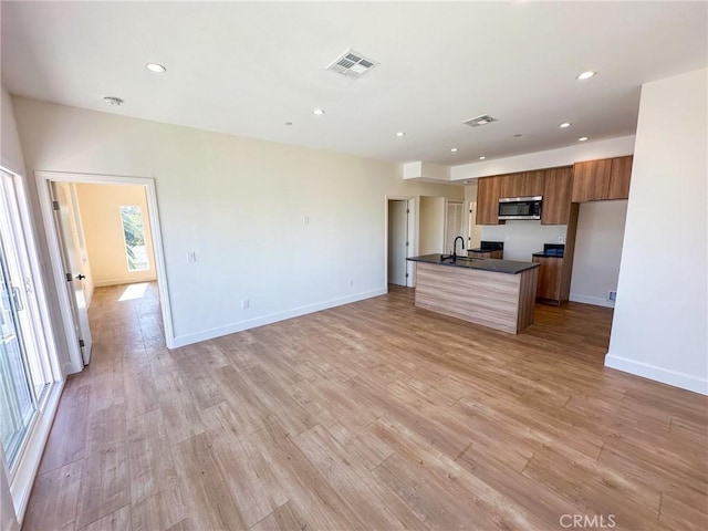 kitchen featuring light hardwood / wood-style floors, sink, and an island with sink