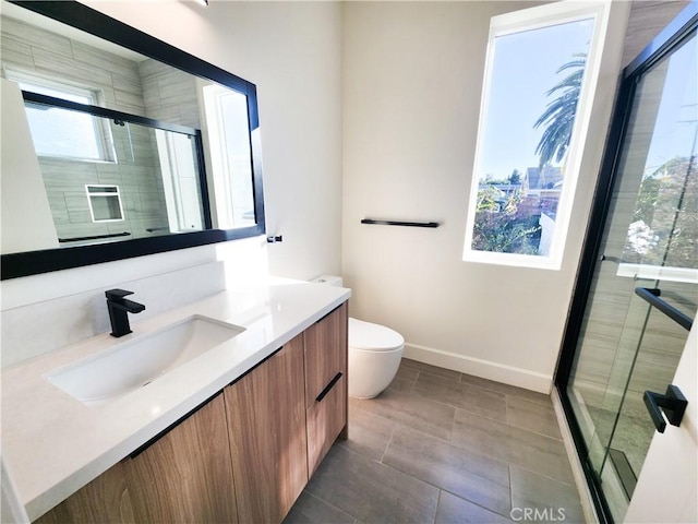 bathroom featuring a shower with door, vanity, and toilet