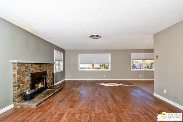 unfurnished living room featuring plenty of natural light, wood-type flooring, and a fireplace