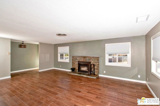 unfurnished living room featuring hardwood / wood-style floors and a stone fireplace