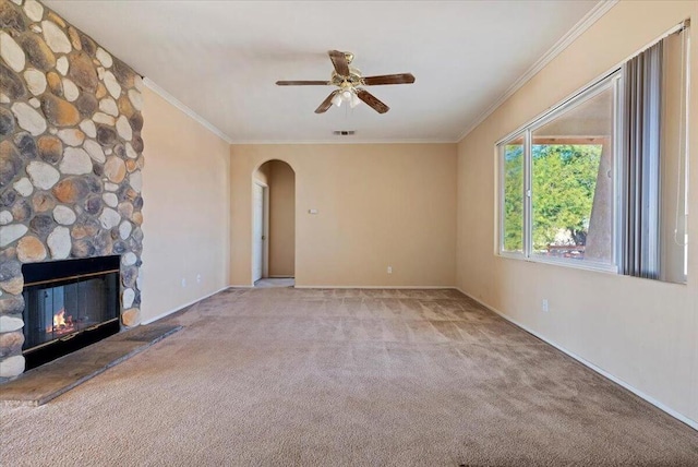 unfurnished living room featuring a stone fireplace, light carpet, ceiling fan, and ornamental molding