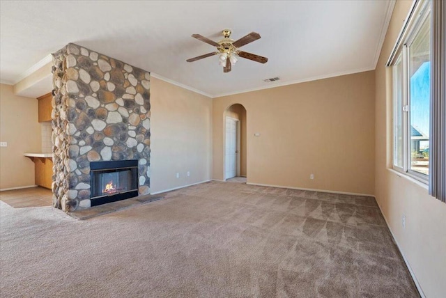 unfurnished living room featuring a fireplace, light colored carpet, ceiling fan, and crown molding