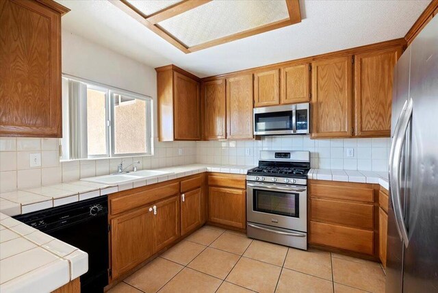 kitchen featuring tile counters, sink, stainless steel appliances, tasteful backsplash, and light tile patterned flooring