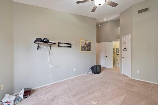 empty room with light carpet, a towering ceiling, and ceiling fan