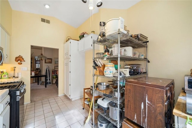 interior space with white cabinets, light tile patterned flooring, lofted ceiling, and appliances with stainless steel finishes