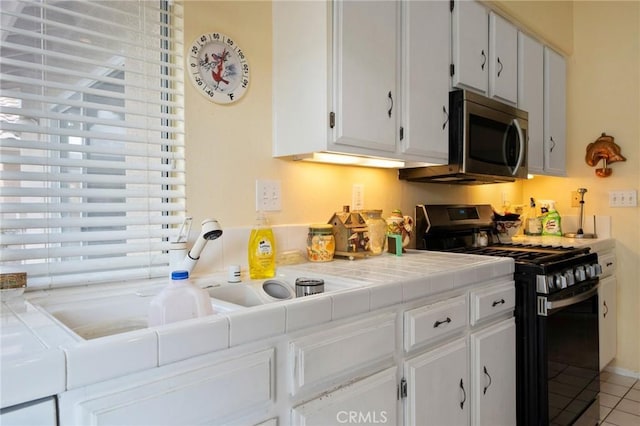 kitchen with white cabinets, tile patterned flooring, stainless steel appliances, and tile countertops