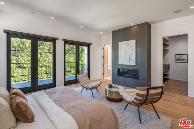 bedroom featuring multiple windows, access to exterior, a fireplace, and light wood-type flooring