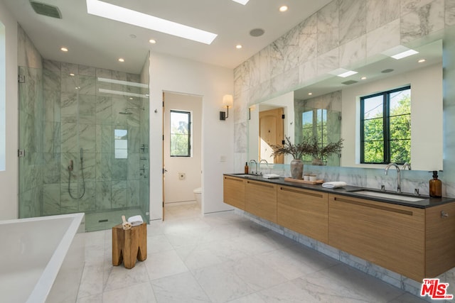 full bathroom featuring a skylight, plus walk in shower, vanity, and toilet