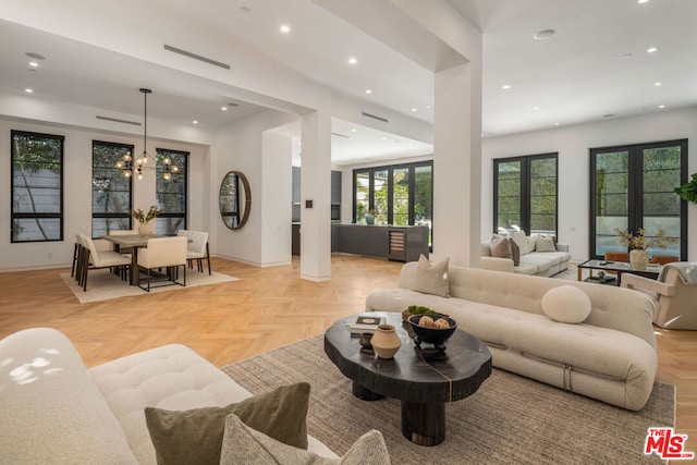 living room with french doors, light parquet flooring, and a notable chandelier