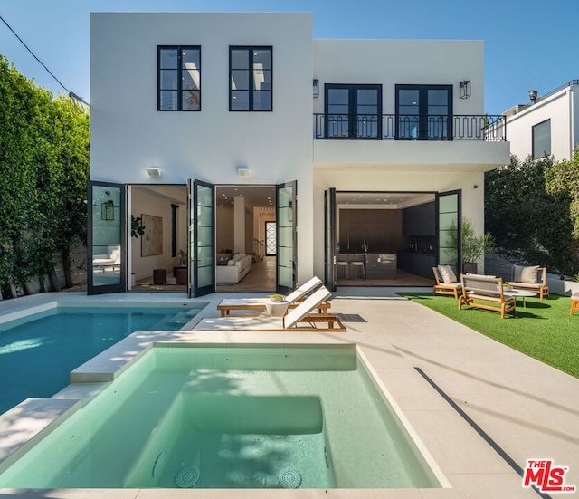 rear view of property with a patio area, a balcony, and a pool with hot tub